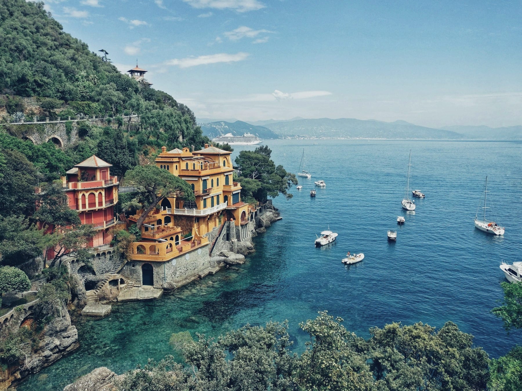 The harbour at Portofino at first light, pastel houses above a still turquoise cove and a handful of boats.